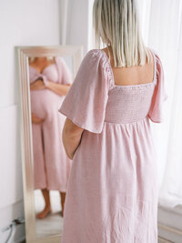 Pregnant mom looking at her belly in the mirror during her maternity session in a Seattle studio