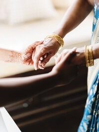 Close-up documentary photograph of intricate henna-detailed hands being held during a luxury wedding at Dover Hall.