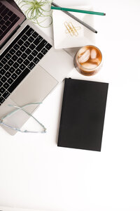 Lap top with Journal and coffee on a white desk