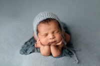Baby boy safely posed in a froggy position on a soft blue backdrop during his newborn session near Mankato, MN with Jennifer Brandes Photography.