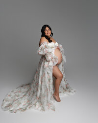 Expecting mother in a soft floral maternity gown posing in a studio maternity photography session captured by Kaitlyn Dawn Photography.