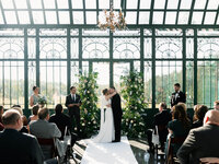 A wide shot of a couple’s first kiss in a glass-walled chapel, capturing the preserving atmosphere and emotion of the ceremony.