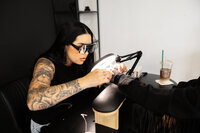 Tattooed makeup artist smiling while working in studio. Photograph by Yucaipa branding photographer Kaitlyn Dawn Photography.