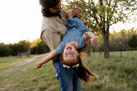 a father holds daughter upside down to get some laughter during their family photo session.