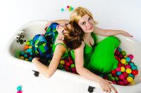 Two artists posed together in a colorful, playful editorial portrait.