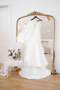 wedding dress and bouquet in front of a grand mirror