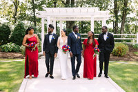 Wedding party walking down path at Lake Pearl dressed in red and black