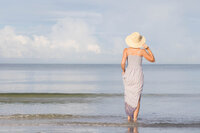 Woman in a sun hat walking into the ocean