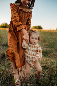 a big sister walks hand in hand with her little sister during their fall family photo session mckinney,texas.