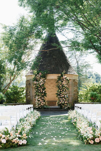 A lush outdoor wedding ceremony aisle and gazebo adorned with overflowing pink and white roses at a luxury North Carolina estate.