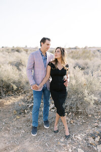 Couple from the Parker family walking hand in hand through a soft desert landscape in Las Vegas, sharing a romantic moment in natural golden light during an outdoor portrait session.
