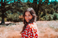 Musician photographed outdoors in a red floral dress for expressive promotional imagery