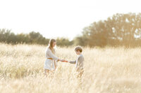 Photo of 2 siblings playing in a grassy field at a DFW park.
