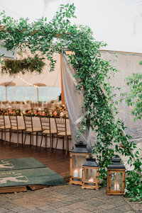 A greenery-covered archway leads into a wedding tent at Spring Lake Golf Club.