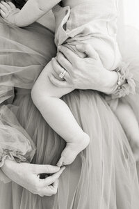 Black and white photo of a mother playing with her babies toes for an in studio photography session.