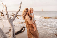 Folly Beach Maternity Photographer -- Pregnant woman poses for Maternity Photos at the Lighthouse Inlet Heritage Preserve on Folly Beach with iconic views of the Morris Island Lighthouse in the distance.