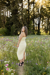 High school senior girl standing in a field of wildflowers during sunset, outdoor senior photography session by Kaitlyn Dawn Photography.