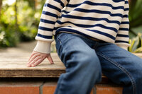 close up of toddler boy sitting on bench while leaning and propping on hand at conservatory
