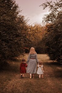 Outdoor photo of a mother holding hands with two children walking