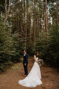 bride and groom standing in the middle of the forest