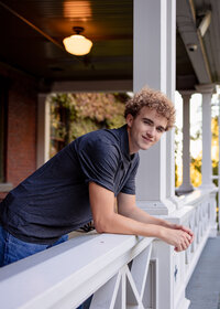 Sam Barlow high school senior boy taking his senior portraits leaning on the white railing at Mcmenamins Edgefield