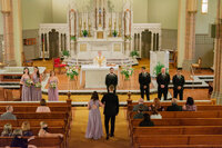 Wedding party walking down the aisle in a Los Angeles church with warm yellow light and a candid documentary feel.