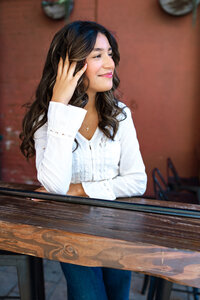 High school senior girl touching her hair while posing by a rustic wooden railing, senior photography by Kaitlyn Dawn Photography.