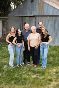 Extended family standing together outside in front of a rustic barn, multiple generations smiling in natural light captured by Kaitlyn Dawn Photography, professional extended family portrait photographer.