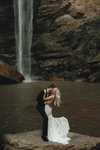 bride and groom walking away at Toccoa falls amoung rose petals