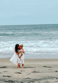 photo of Ellie Johnson, owner of Sophisticated Grace Studio, hugging her stepson on a beach