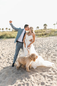 bride & groom kissing on beach with dog