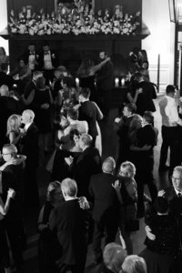 Black and white overhead photograph of wedding guests dancing during an energetic reception celebration