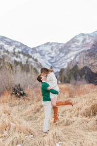 Rocky Mountain National Park engagement photo—couple kissing in a golden meadow with mountain peaks