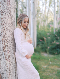 Pregnant woman leading on the tree looking pensive