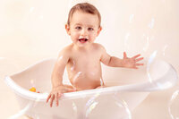 laughing one year old in bath with floating bubbles in studio