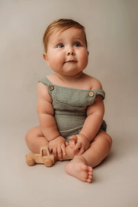 Baby looks at his mother during Baby Milestone Portrait Session at Holy City Babies Portrait Studio in Charleston, SC.