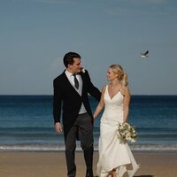Couple on their wedding day walking on the beach at Carbis Bay Hotel