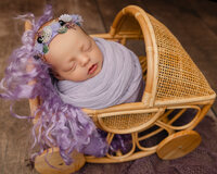 Newborn baby wrapped in lavender resting on textured purple layers. Photographed by Inland Empire newborn photographer Kaitlyn Dawn Photography.