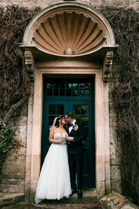 Colourful Wedding photography at the swan inn bibury capturing bride and groom in doorway candid style