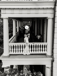 Timeless black and white editorial portrait of a couple kissing on the historic balcony of the Edmondston-Alston House in Charleston, SC.