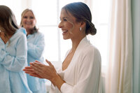 Bride smiling and clapping her hands while getting ready on her wedding day at Burritt on the Mountain in Huntsville, Alabama, captured by Perry Hancock.