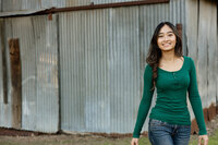 High school senior girl standing in a grassy field during golden hour wearing a green dress, senior portrait by Kaitlyn Dawn Photography.