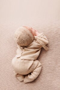Newborn baby posed in minimalist soft neutral studio portrait