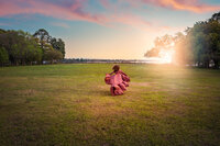 Child in dusty pink dress twirling at sunset in an open field during a family portrait session in New Bern NC