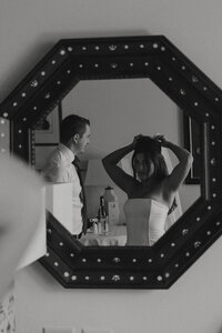 bride putting on her veil in the mirror while her husband watches in brunswick, georgia 