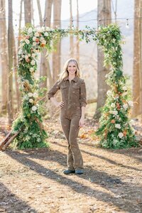 Owner of Flowergirl Cville and Maison Charlottesville standing in front of floral wedding arch.