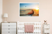 Framed sunset maternity portrait displayed above a crib in a neutral nursery