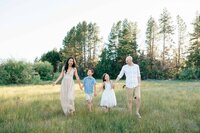 Family walking hand‑in‑hand through a natural outdoor space.