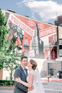bride and groom kissing in front of one of Providenc's iconic murals