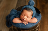 Baby boy posed in a bucket wearing a blue bonnet. Mankato area newborn & family photography, southern minnesota photographer
